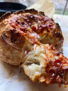 a piece of bread with cheese and pepperoni on it sitting on top of wax paper