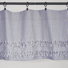 the blue and white striped curtain is hanging from a metal rod with two black hooks