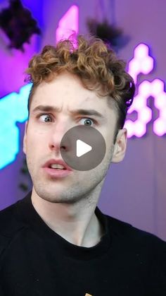 a young man with curly hair is making a face and looking at the camera while wearing a black t - shirt