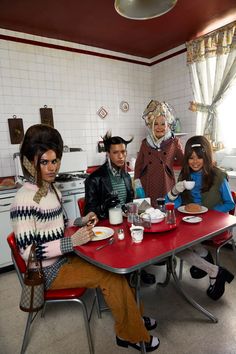 four people sitting at a table with plates and cups