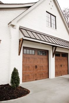 a white house with two brown garage doors