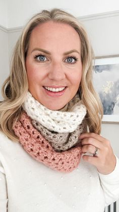 a woman wearing a white sweater and a crocheted cowl scarf is smiling at the camera