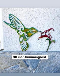 the hummingbird is painted on the side of the building and has two flowers in it