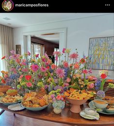 a wooden table topped with lots of plates and bowls filled with different types of food