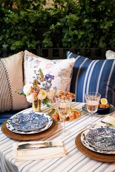 a table set with plates, silverware and flowers in vases on top of it