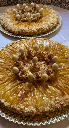 two pies with nuts on them sitting on top of a table