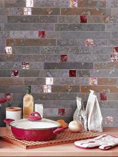 a red pot sitting on top of a wooden cutting board next to a wall covered in tiles