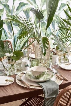 the table is set with plates, cups and plants