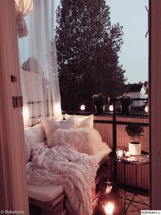 a bed sitting on top of a wooden floor next to a window covered in white blankets