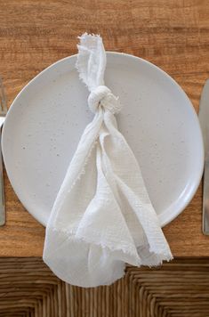 a white plate topped with a napkin next to a fork and knife on top of a wooden table