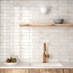 a kitchen with white tiles and wooden shelves on the wall, two pears are sitting on the counter