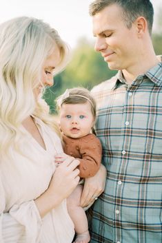 a man and woman holding a baby in their arms