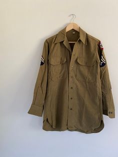 "Vintage 1940s WWII olive drab wool long sleeve button front U.S. Army military uniform shirt. Features Staff Sergeant patches, a gas flap, cuff gussets + two flap chest pockets. Has a spot + three small holes on back of left sleeve, as well as a spot on the front {see images}. BRAND: US ARMY WWII Pacific Theater Material: 100% Wool Condition: Excellent Vintage Condition!  Please refer to photos. Size:  32 / 14.5 Please check measurements thoroughly before purchasing Measurements are taken layin Military Style Long Sleeve Shirt With Buttons, Military Long Sleeve Work Shirt, Military Style Shirt With Button Closure For Fall, Vintage Olive Long Sleeve Outerwear, Olive Vintage Long Sleeve Outerwear, Retro Long Sleeve Khaki Shirt, Vintage Olive Long Sleeve Tops, Vintage Khaki Button-up Shirt, Vintage Long Sleeve Shirt With Button Cuffs