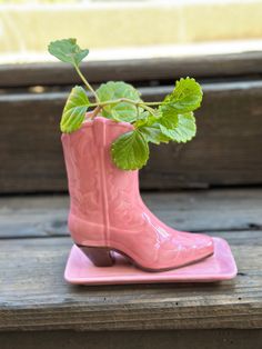 a pink boot shaped planter sitting on top of a wooden bench