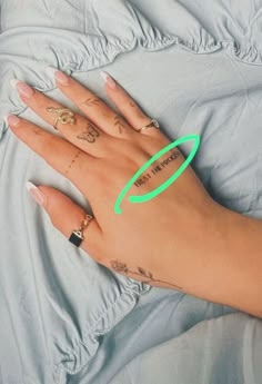 a woman's hand with tattoos on it and a green ring around her finger