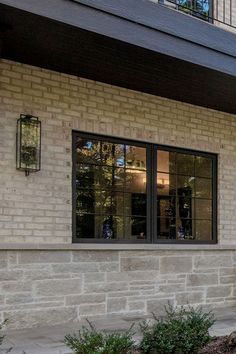 a red fire hydrant sitting in front of a brick building with two large windows