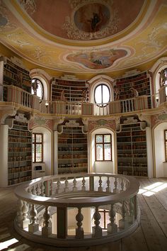 the circular room has many bookshelves and windows in it, as well as round balconies