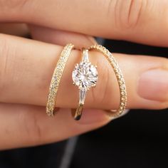 a close up of a person's hand holding a ring with a diamond on it