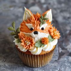 a cupcake with frosting and flowers on it is sitting on a table top