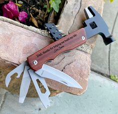 a knife that is sitting on top of a rock next to a flower pot with flowers in it