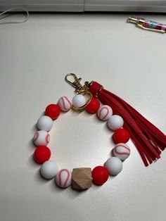 a red and white beaded bracelet with tassels on top of a table