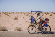 a man riding a bike with a solar panel on it's back in the desert