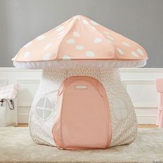 a pink and white tent with polka dots on it in a child's room