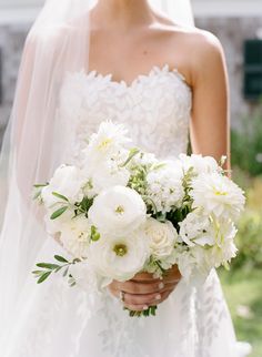 a bride holding a bouquet of white flowers