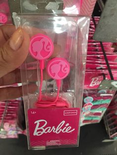 someone is holding up some pink earbuds in a box with the word barbie on it