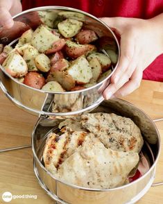 two metal pans filled with food on top of a wooden table