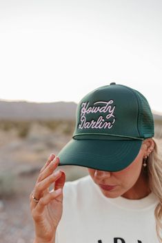 Say hello to the perfect summer accessory with our Howdy Darlin' Trucker Hat! Made with a classic trucker design, this green hat features "Howdy Darlin'" embroidered on the front. Keep cool and stylish all summer long with this trendy hat! Paired with THE HOLD YOUR HORSES GRAPHIC TEE IN IVORY, THE 90'S FLARE JEANS IN BLACK BY VERVET, and THE MIMI COWGIRL BOOTS IN WHITE. Howdy Darlin' embroidered on front in pink Trucker style Adjustable snapback 100% polyester Due to sanitary reasons, accessorie Green Trucker Baseball Cap With Flat Brim, Green Trucker Cap With Flat Brim, Green Trucker Hat For Spring, One Size Fits Most, Green Adjustable Trucker Hat With Short Brim, Adjustable Green Trucker Hat With Short Brim, Green Trucker Hat With Curved Brim, Trendy Green Trucker Hat, Trendy Green Baseball Cap For Spring, Green Spring Trucker Hat