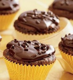 cupcakes with chocolate frosting and sprinkles on them sitting on a plate