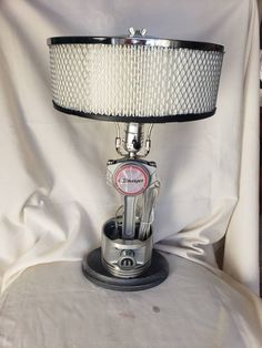 a lamp sitting on top of a white chair next to a white cloth covered wall