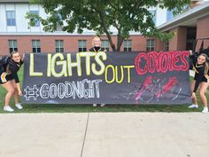 three cheerleaders holding a sign that says lights out cookies