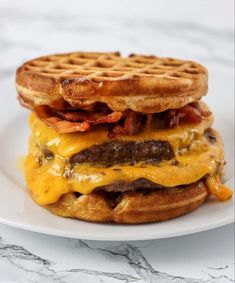 a cheeseburger with bacon and waffles on a white plate