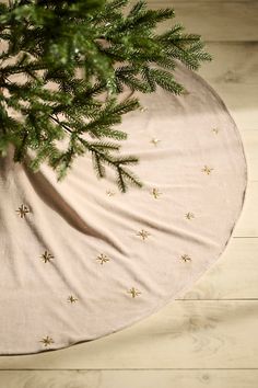 a tree skirt with gold stars on it sitting on a wooden floor next to a potted plant