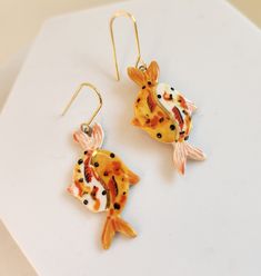 "Porcelain ceramic earrings, hand painted with a variety of glazes, including 22k gold luster accents. Hook is plated 18k gold over raw brass. Ceramic pieces are painted solid gold on the back. Each earring measures approximately 2.25\" long and weighs less than a quarter of an ounce.  Patterns will vary from photo: every piece is made to order and painted patterns will not be identical. Production time is 2-3 weeks.  Earrings will ship wrapped in tissue paper in a box, suitable for gifting." Yellow Gold Enamel Earrings As Gift, Artsy Enamel Earrings As Gift, Orange Enamel Earrings As A Gift, Orange Enamel Earrings For Gift, Orange Enamel Earrings For Gifts, Hand Painted Gold Dangle Jewelry, Nickel-free Yellow Gold Enamel Earrings, Hand Painted Enamel Artsy Earrings, Black Enamel Earrings For Gift