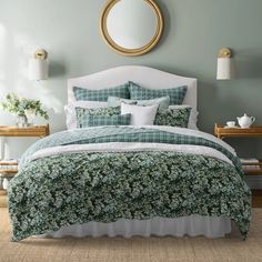 a bed with green and white bedspread in a bedroom next to a mirror