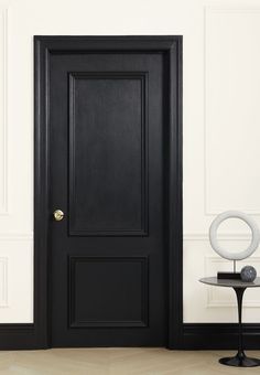 an empty room with a black door and side table on the floor next to it