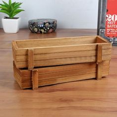 a wooden crate sitting on top of a table next to a potted planter