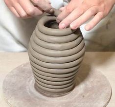 a person is making a vase out of clay