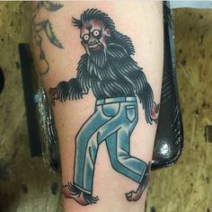 a man's leg with a tattoo of a hairy creature on it and blue jeans