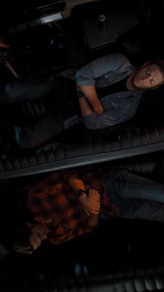 two people are laying down on the floor next to each other in a dark room