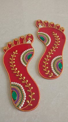 two pairs of red and green decorated shoes on a white surface with gold trimmings