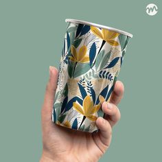 a hand holding a paper cup with leaves on it