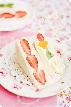 a piece of cake on a plate with strawberries and kiwi slices cut in half