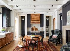 a kitchen and dining room with black cabinets, wood floors, and rugs on the floor