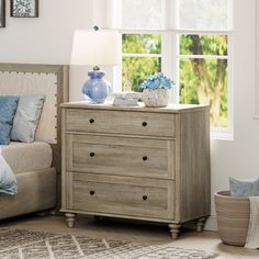 a bedroom scene with focus on the dresser and bed side table in the foreground