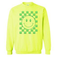 a yellow sweatshirt with a smiley face on the front and green checkered squares around it