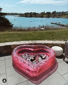 an inflatable heart shaped object on the ground next to a body of water